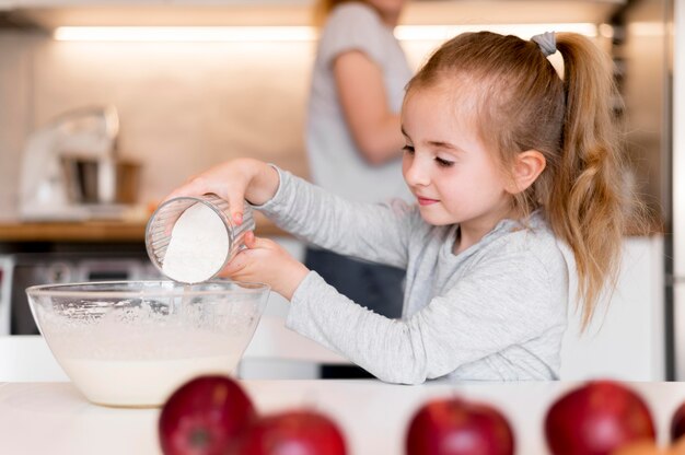 Vista frontale della bambina che cucina a casa