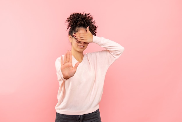 Vista frontale della bella femmina che copre il viso in rosa