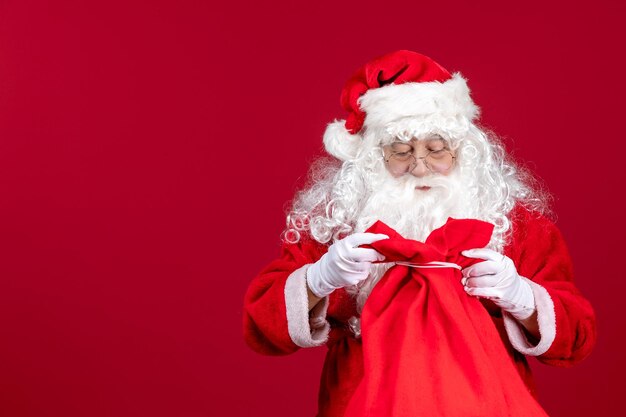 Vista frontale della borsa di apertura di babbo natale piena di regali per i bambini in una vacanza rossa