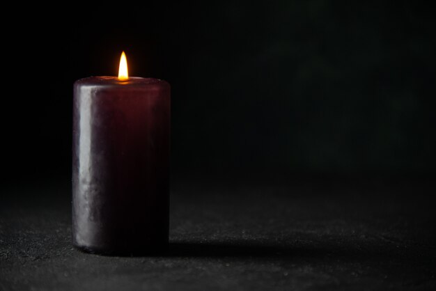 Vista frontale della candela viola su oscurità