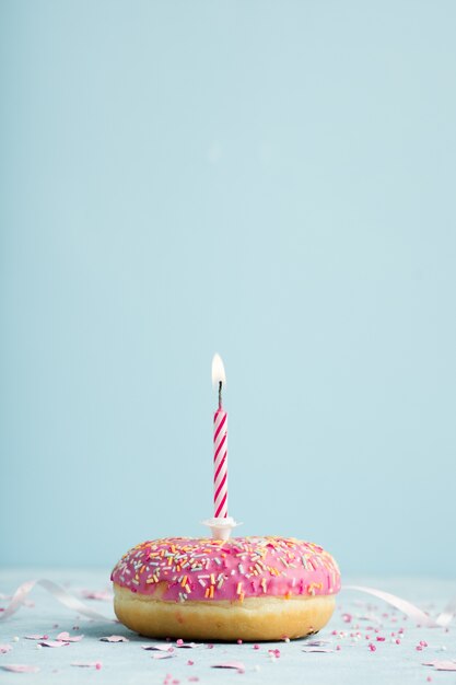 Vista frontale della ciambella di compleanno con la candela accesa e lo spazio della copia