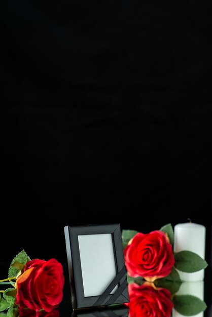 Vista frontale della cornice con candela e rosa rossa su fondo nero