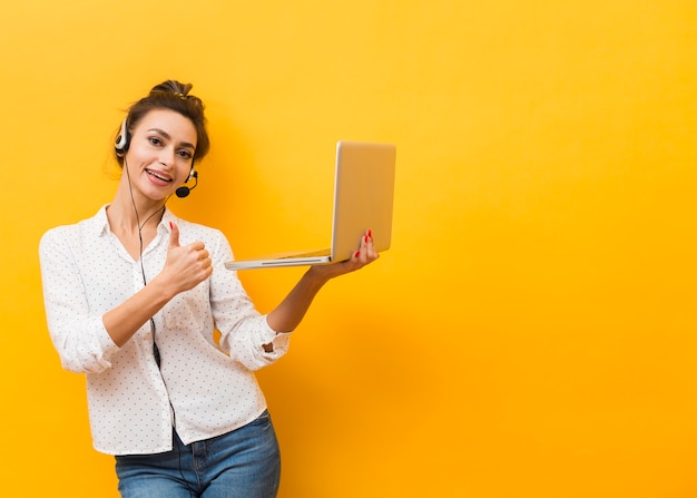 Vista frontale della cuffia avricolare da portare della donna e del computer portatile della holding