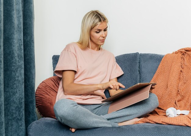 Vista frontale della donna a casa sul divano utilizzando tablet