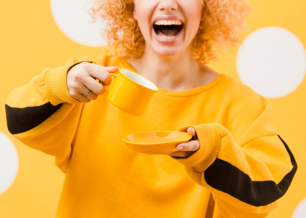 Vista frontale della donna bionda con la tazza gialla