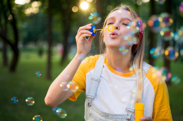 Vista frontale della donna che gioca all'aperto con le bolle