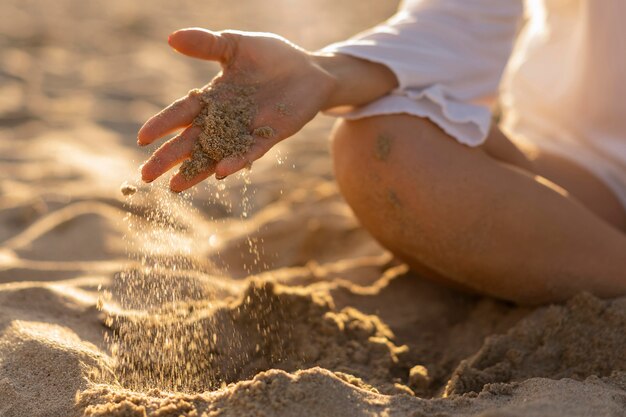 Vista frontale della donna che gioca con la sabbia della spiaggia