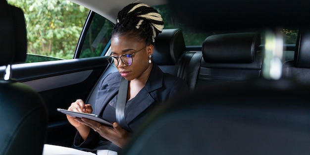 Vista frontale della donna che guarda su tablet mentre è seduto sul sedile posteriore dell'auto