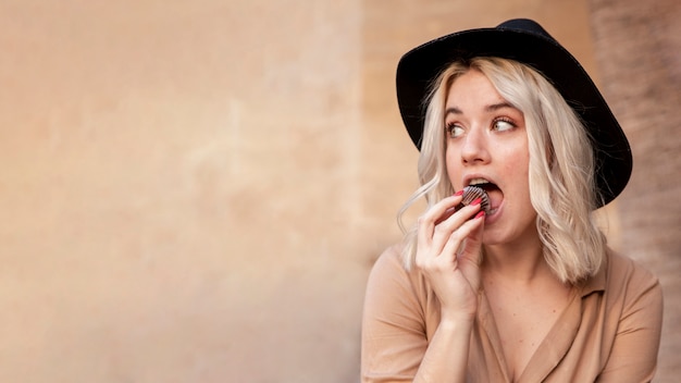 Vista frontale della donna che mangia bigné con lo spazio della copia