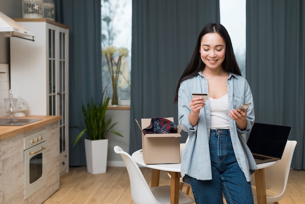 Vista frontale della donna che ordina online mentre esaminando la carta di credito