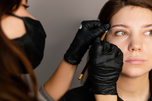 Vista frontale della donna che ottiene un trattamento per le sopracciglia dal medico femminile