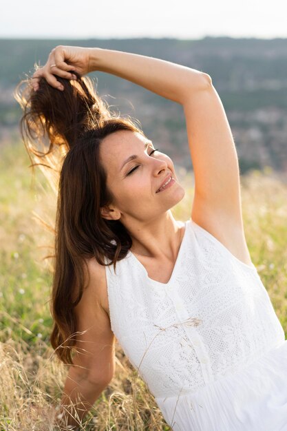 Vista frontale della donna che posa nell'erba all'aperto