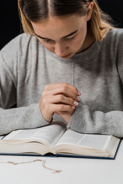 Vista frontale della donna che prega e legge dalla Bibbia