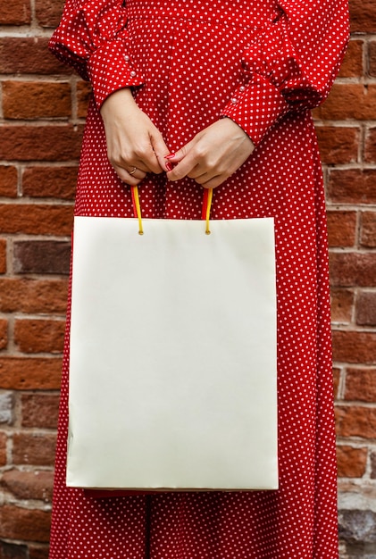 Vista frontale della donna che propone all'esterno con la borsa della spesa
