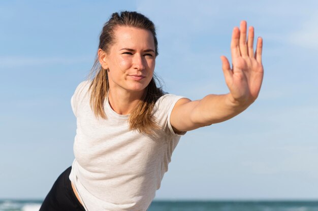 Vista frontale della donna che si estende sulla spiaggia