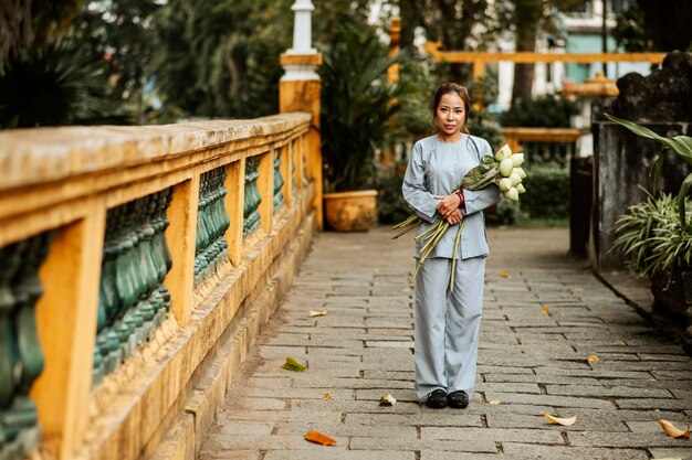 Vista frontale della donna che tiene il mazzo di fiori al tempio