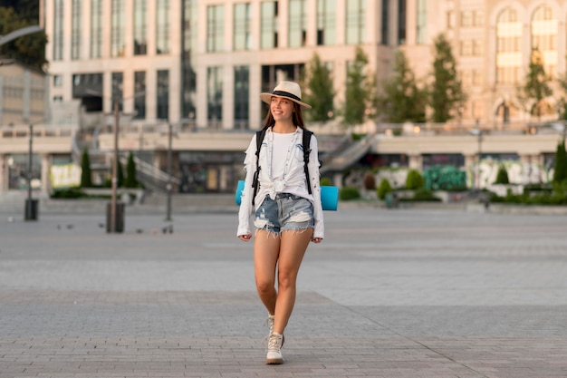 Vista frontale della donna con cappello che trasporta zaino mentre si viaggia da soli