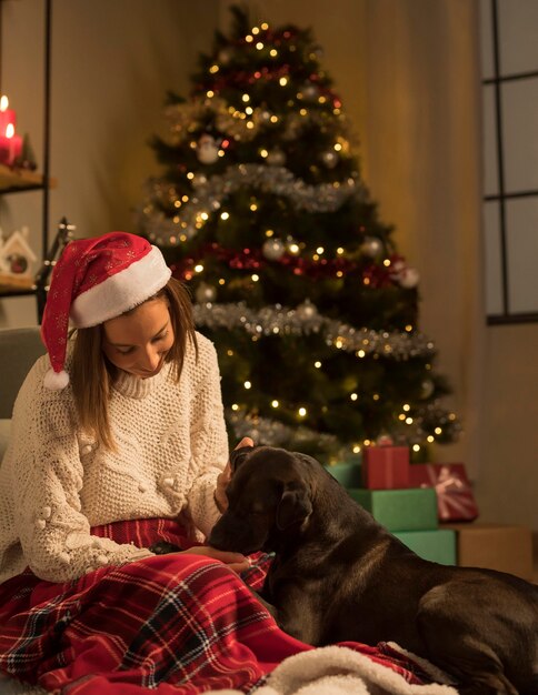 Vista frontale della donna con cappello santa e il suo cane a Natale