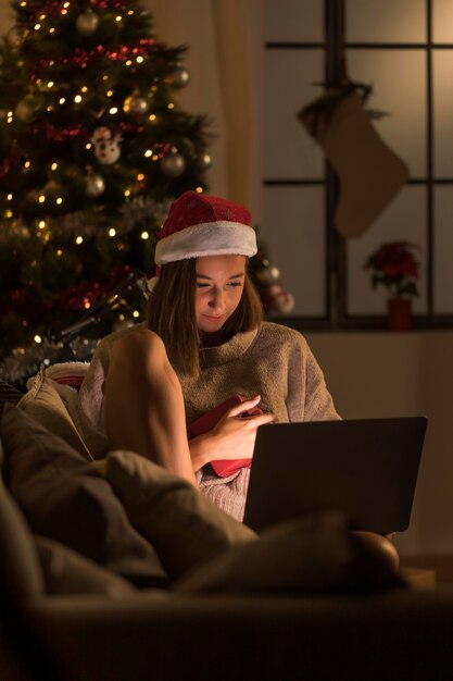Vista frontale della donna con il computer portatile della tenuta del cappello della Santa sul giro
