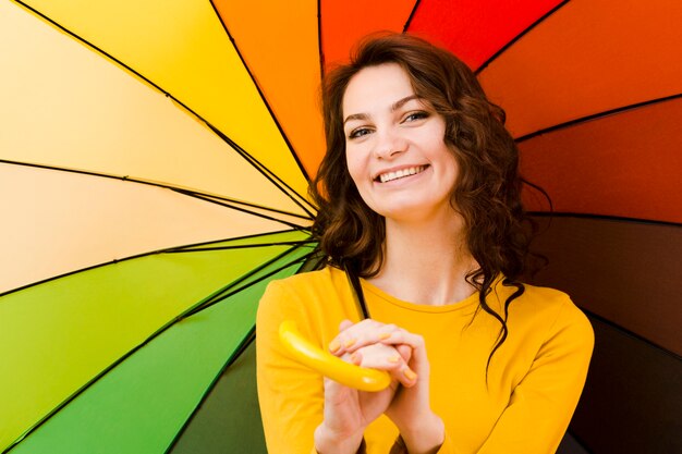 Vista frontale della donna con l'ombrello dell'arcobaleno