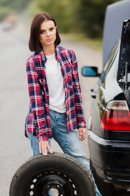 Vista frontale della donna con la gomma di automobile