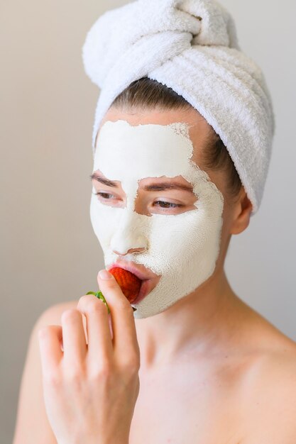 Vista frontale della donna con la maschera che mangia fragola