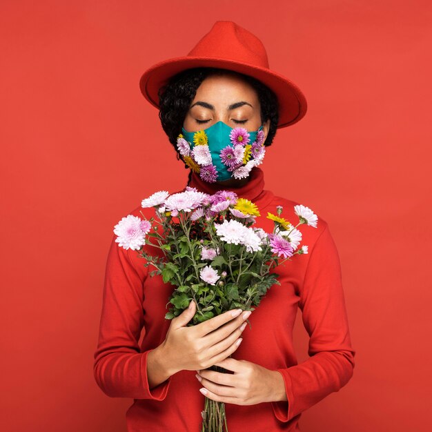 Vista frontale della donna con la maschera che tiene i fiori