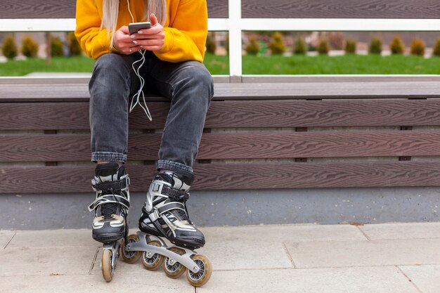 Vista frontale della donna con le lame del rullo che tengono smartphone