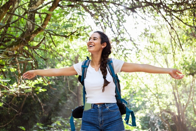 Vista frontale della donna con lo zaino ad esplorare la vita all'aria aperta