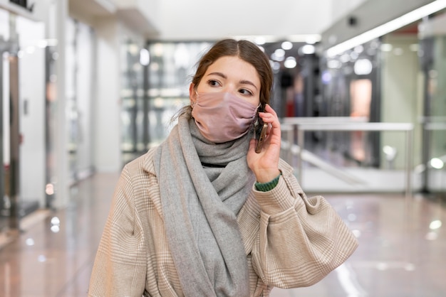 Vista frontale della donna con mascherina medica parlando al telefono