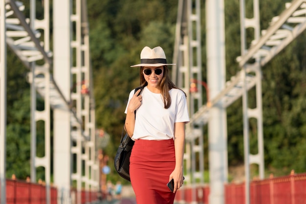 Vista frontale della donna con occhiali da sole e cappello che viaggiano da soli