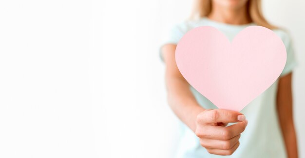 Vista frontale della donna defocused che tiene a forma di cuore con lo spazio della copia