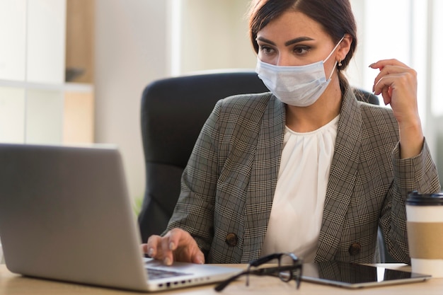 Vista frontale della donna di affari che lavora con la maschera per il viso alla scrivania