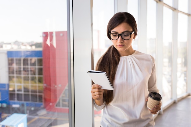 Vista frontale della donna di affari con caffè e taccuino