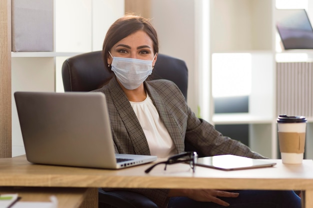 Vista frontale della donna di affari con la maschera per il viso in ufficio