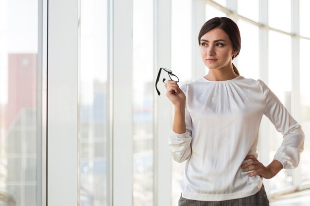 Vista frontale della donna di affari seducente che posa con gli occhiali