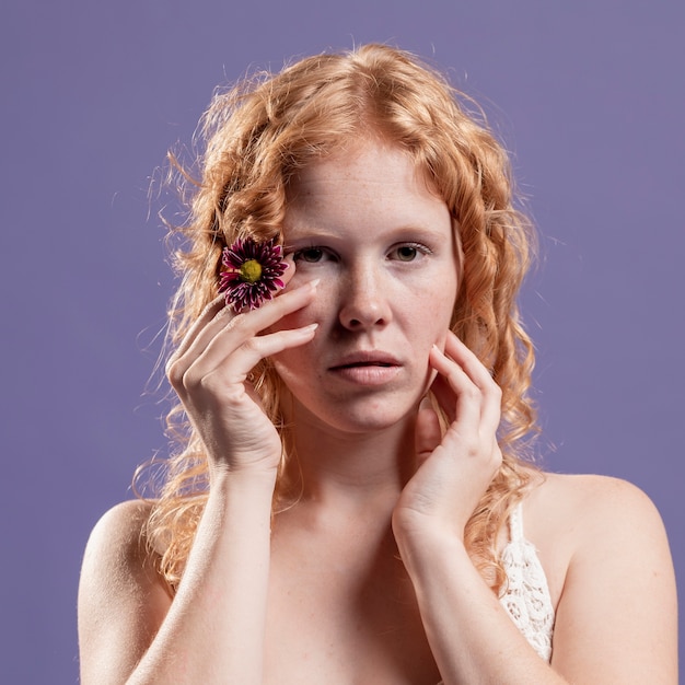 Vista frontale della donna di redhead che propone con le suoi mani e fiore