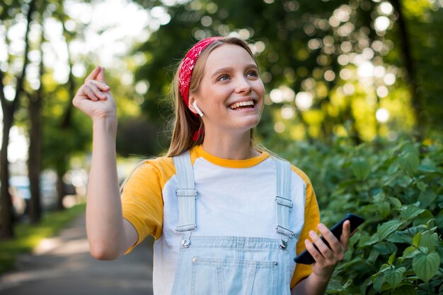 Vista frontale della donna di smiley all'aperto con lo smartphone