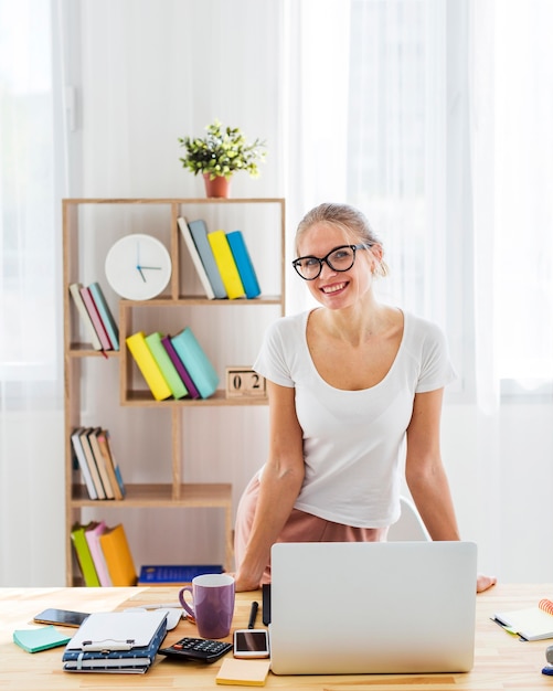 Vista frontale della donna di smiley allo scrittorio che lavora dalla casa