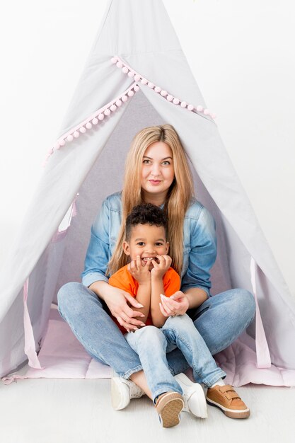 Vista frontale della donna e del giovane ragazzo che posano in tenda