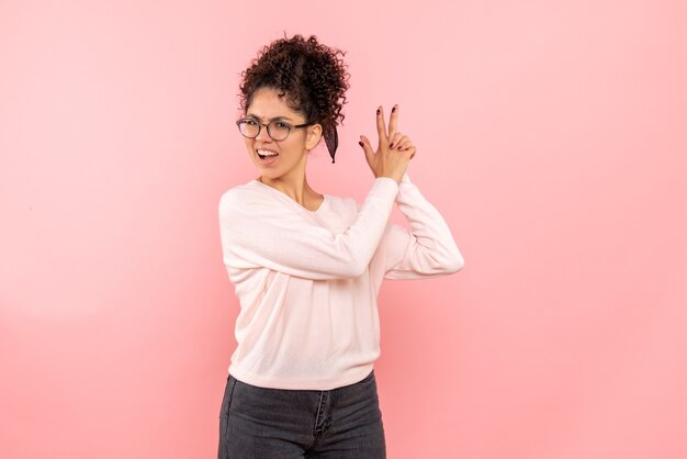 Vista frontale della donna graziosa che imita la pistola che tiene sul rosa