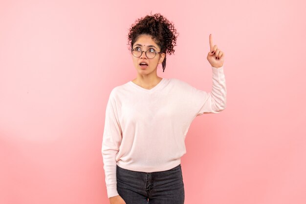 Vista frontale della donna graziosa che pensa sulla parete rosa