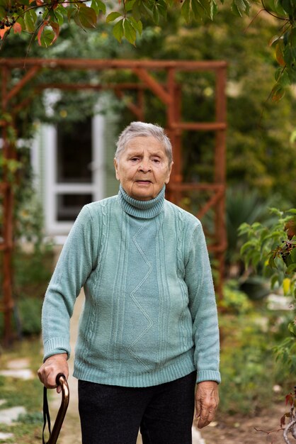 Vista frontale della donna più anziana che cammina con la canna