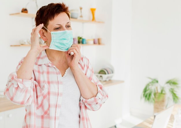 Vista frontale della donna più anziana che mette sulla maschera medica