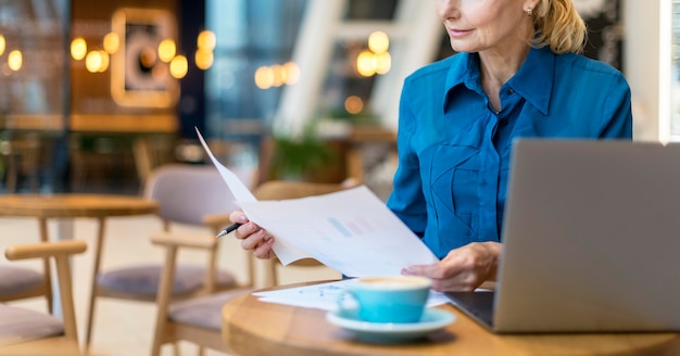 Vista frontale della donna più anziana di affari che lavora con documenti e laptop