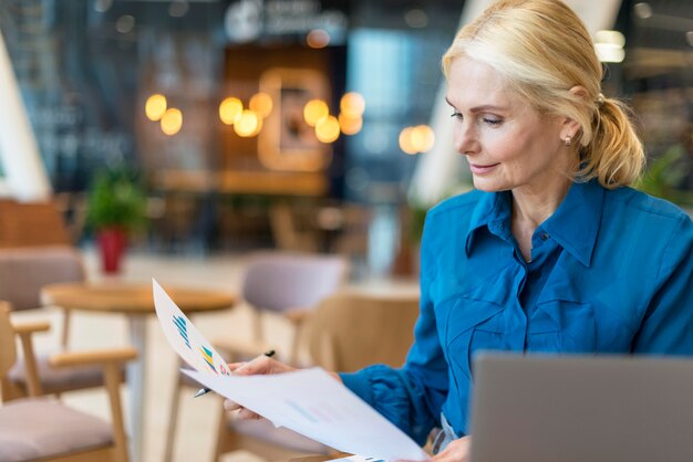 Vista frontale della donna più anziana di affari che lavora con documenti e laptop