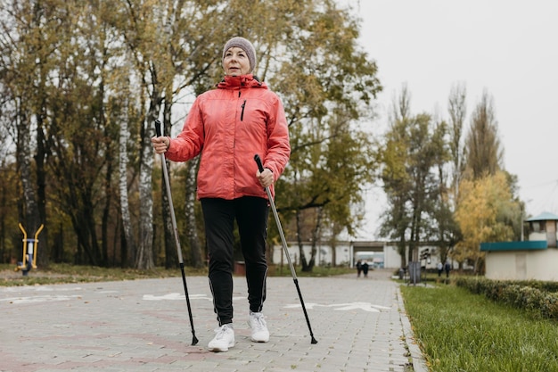 Vista frontale della donna senior all'aperto con bastoncini da trekking