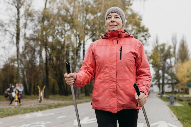 Vista frontale della donna senior di smiley all'aperto con bastoncini da trekking