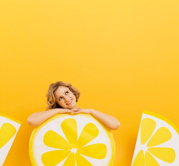 Vista frontale della donna sorridente che posa con lo spazio della decorazione e della copia delle fette del limone