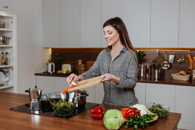 Vista frontale della donna sorridente che prepara il cibo in cucina a casa